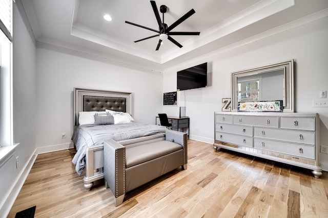 bedroom featuring visible vents, baseboards, light wood-type flooring, and a tray ceiling