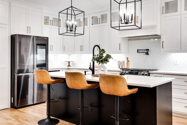 kitchen with stove, an island with sink, smart refrigerator, and light countertops