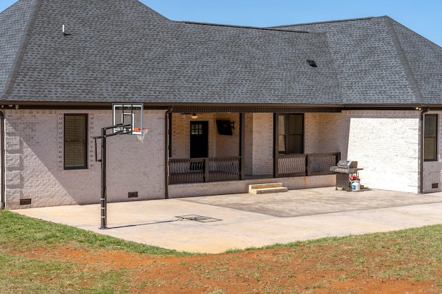 rear view of property featuring crawl space, a porch, a shingled roof, and brick siding