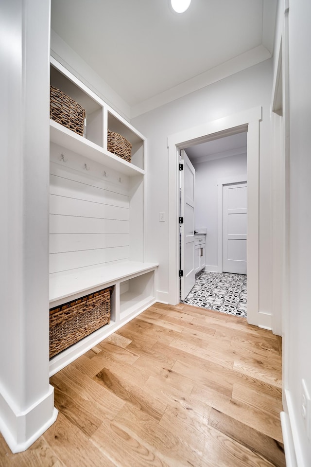 mudroom featuring light wood finished floors and ornamental molding