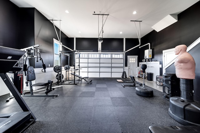 exercise room with recessed lighting, a garage, and a towering ceiling