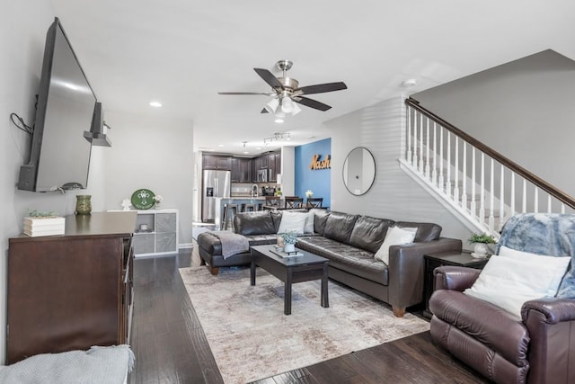 living area featuring stairs, dark wood-style flooring, and ceiling fan