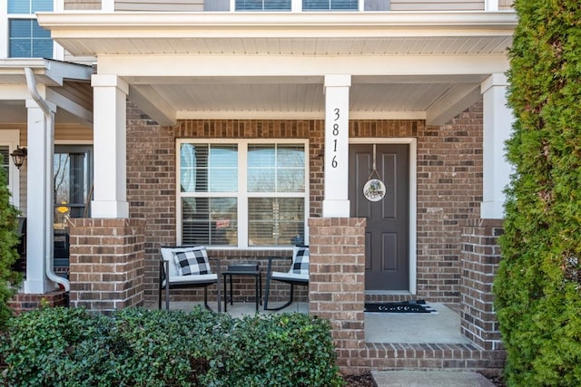 doorway to property with brick siding and covered porch