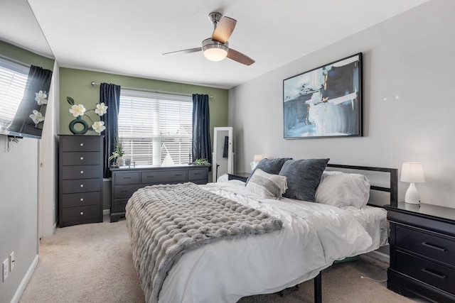 bedroom featuring baseboards, light colored carpet, and ceiling fan