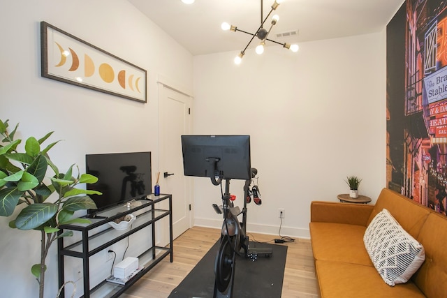 workout room featuring visible vents, baseboards, an inviting chandelier, and wood finished floors