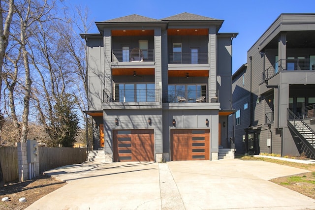 modern home with fence, roof with shingles, concrete driveway, an attached garage, and a balcony