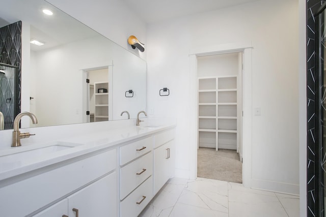 full bathroom with a sink, a walk in closet, and marble finish floor