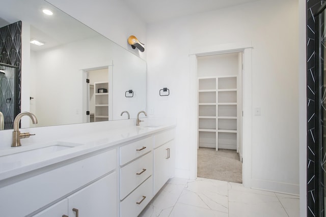 full bathroom featuring a sink, a walk in closet, and marble finish floor