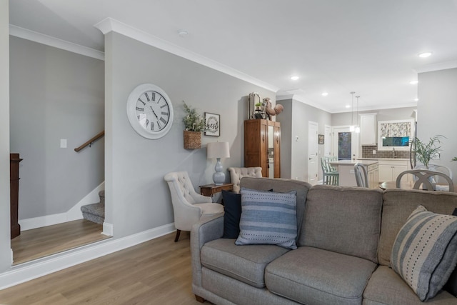 living room featuring stairs, baseboards, light wood finished floors, and ornamental molding