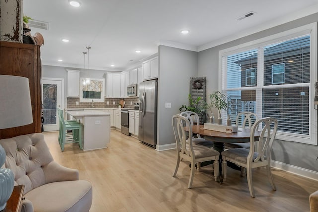 kitchen featuring ornamental molding, light countertops, appliances with stainless steel finishes, a kitchen breakfast bar, and backsplash