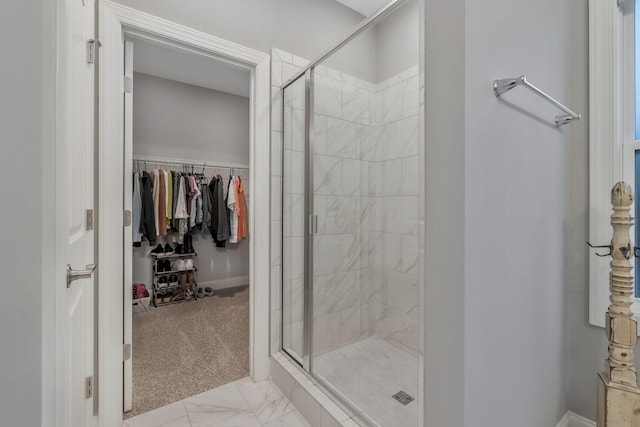 bathroom with a spacious closet, a shower stall, and marble finish floor