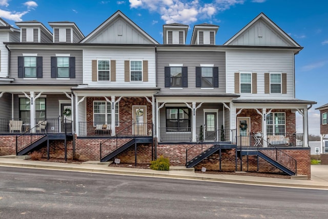 townhome / multi-family property featuring board and batten siding, stairway, and covered porch