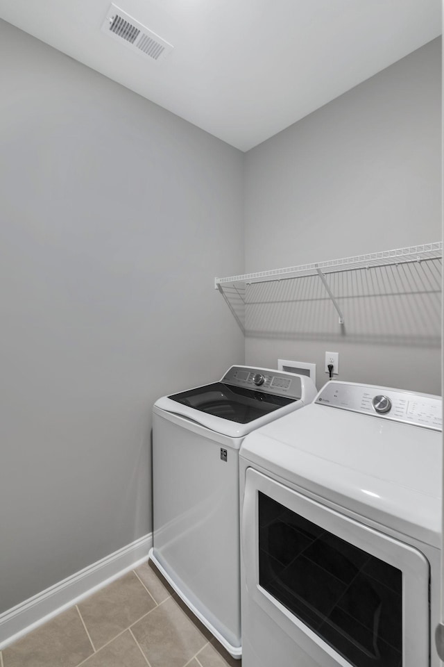 clothes washing area with baseboards, visible vents, laundry area, light tile patterned flooring, and washer and dryer