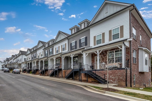 multi unit property featuring covered porch, brick siding, board and batten siding, and a residential view