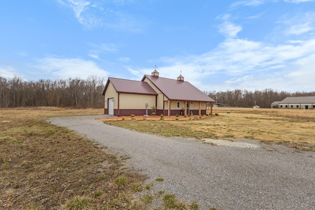 view of front of house with metal roof, a garage, a chimney, and driveway