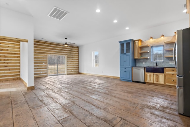 kitchen with visible vents, dark countertops, rustic walls, stainless steel appliances, and light wood finished floors