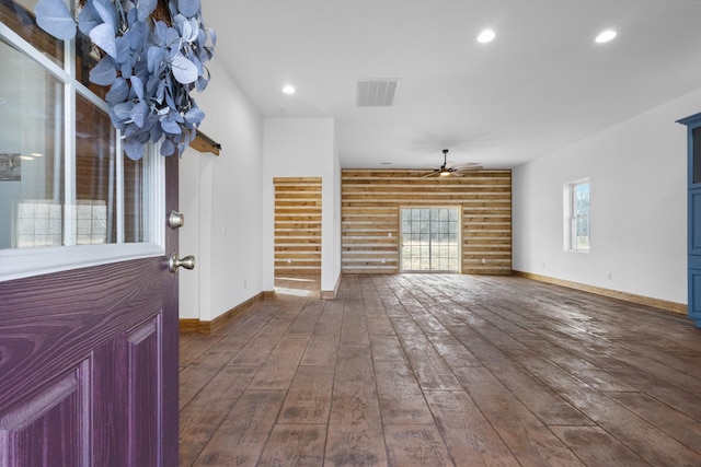 unfurnished living room with visible vents, baseboards, dark wood-style floors, recessed lighting, and rustic walls