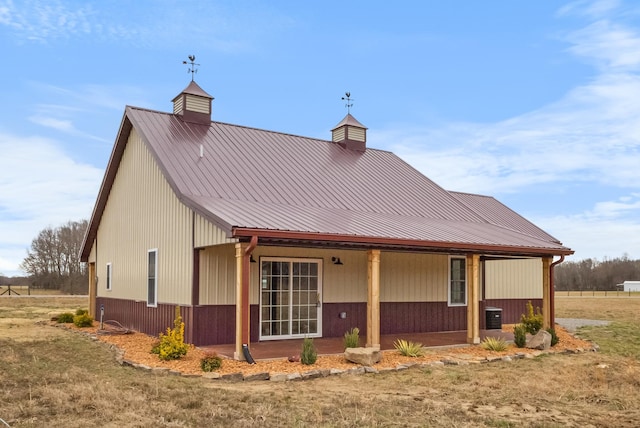 back of property with metal roof, central AC unit, a chimney, and a porch