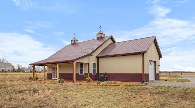 view of front of property with covered porch, a chimney, metal roof, a garage, and driveway