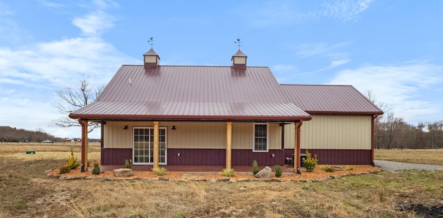 rear view of house with metal roof, covered porch, and a chimney