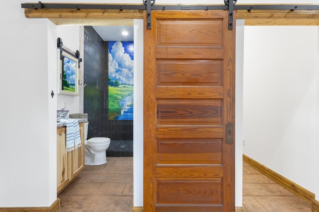 bathroom featuring vanity, toilet, wood finished floors, and baseboards