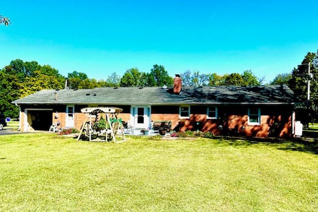 back of property featuring a garage, a yard, and a chimney