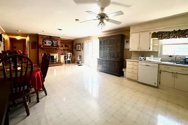 kitchen with a sink, light floors, dishwasher, and a brick fireplace