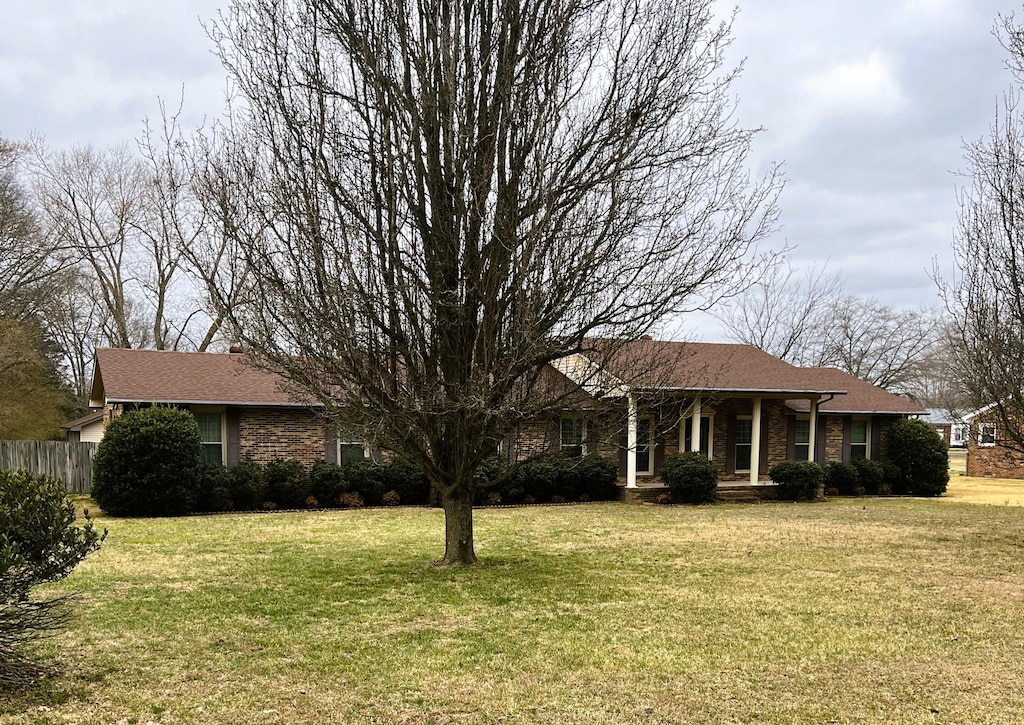 single story home featuring brick siding, a front lawn, and fence