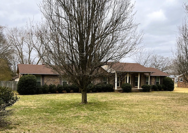 single story home featuring brick siding, a front lawn, and fence