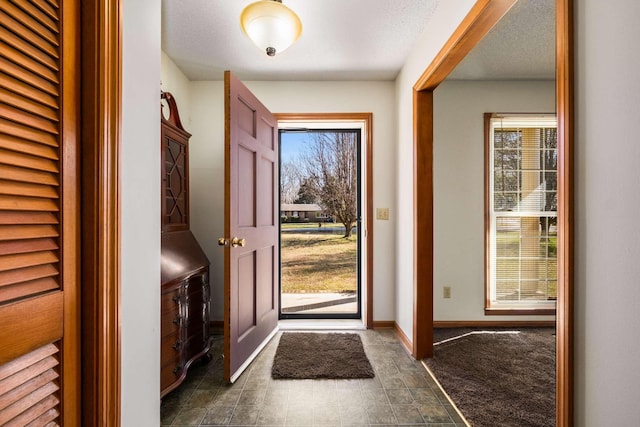 foyer entrance featuring baseboards and a textured ceiling