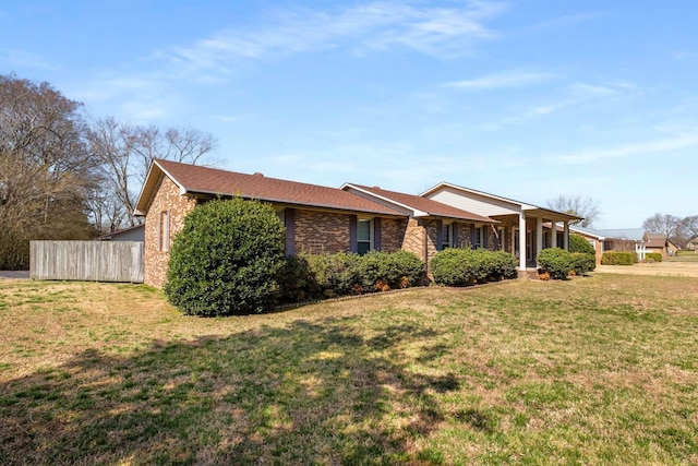 view of front of home with brick siding, a front lawn, and fence