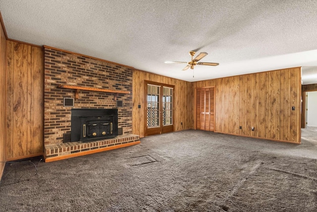 unfurnished living room featuring carpet flooring, a textured ceiling, and wooden walls