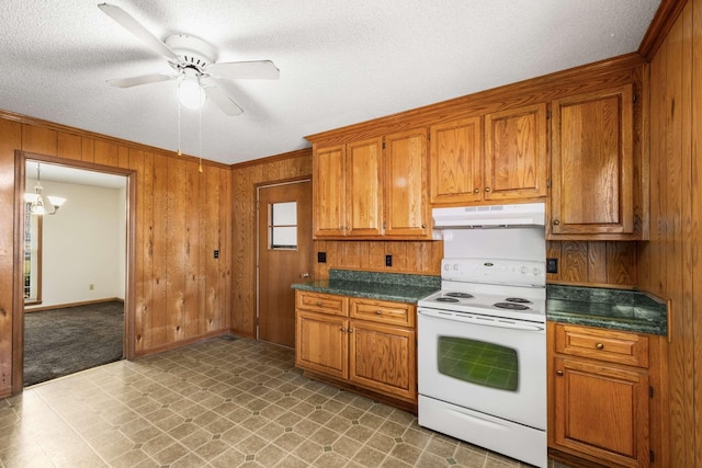 kitchen with under cabinet range hood, wood walls, brown cabinetry, and white range with electric cooktop