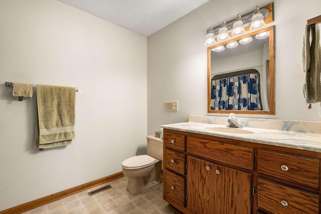 full bath with vanity, baseboards, visible vents, a textured ceiling, and toilet