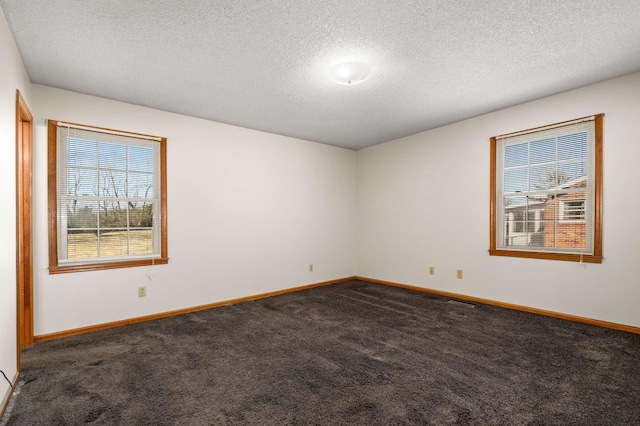 spare room with baseboards, dark carpet, and a textured ceiling