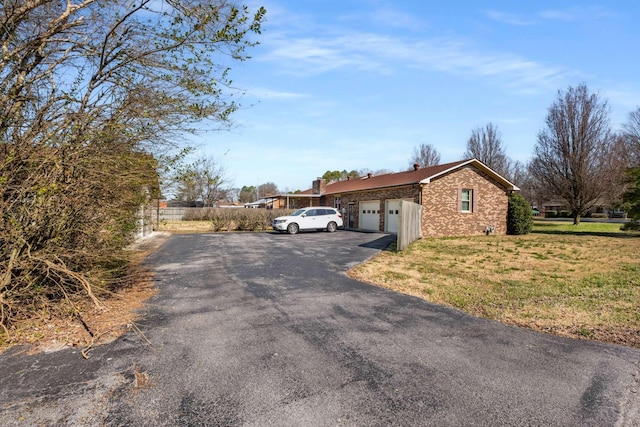 view of side of property with an attached garage, a lawn, and driveway