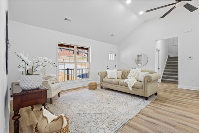 living area with light wood finished floors, stairway, a ceiling fan, and visible vents