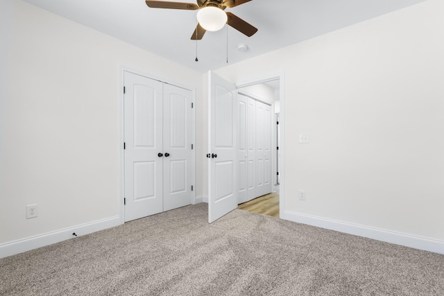 unfurnished bedroom featuring light carpet, ceiling fan, two closets, and baseboards