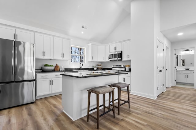 kitchen featuring white cabinets, appliances with stainless steel finishes, a breakfast bar, and a sink