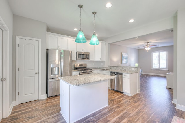 kitchen with a peninsula, white cabinets, dark wood-style flooring, and appliances with stainless steel finishes