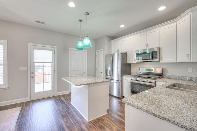 kitchen with visible vents, a kitchen island, dark wood finished floors, a sink, and stainless steel appliances