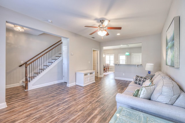 living area featuring stairway, wood finished floors, visible vents, baseboards, and ceiling fan