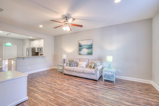 living area with visible vents, baseboards, recessed lighting, wood finished floors, and a ceiling fan