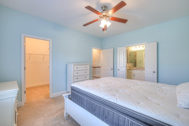 bedroom featuring light carpet, ensuite bathroom, a closet, baseboards, and a spacious closet