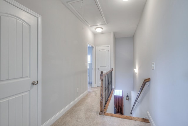 corridor featuring baseboards, an upstairs landing, attic access, and carpet flooring