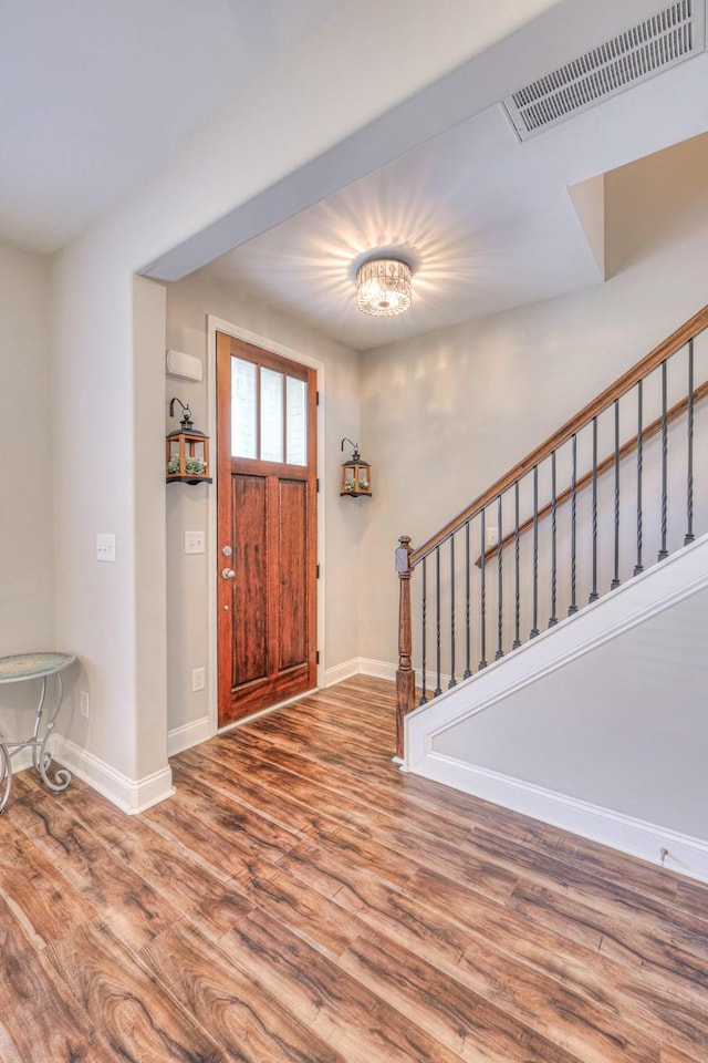 foyer entrance featuring stairs, wood finished floors, visible vents, and baseboards