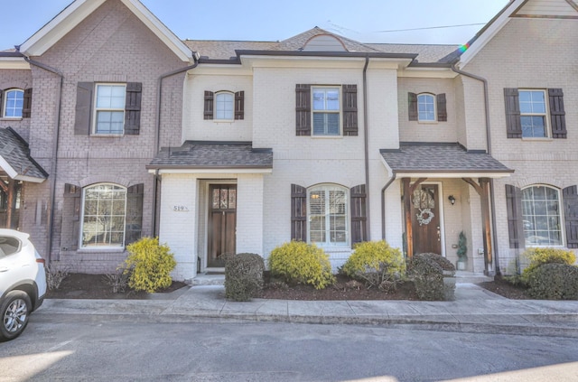 multi unit property with brick siding and a shingled roof