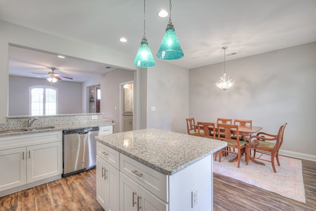 kitchen with a kitchen island, dishwasher, wood finished floors, white cabinets, and a sink