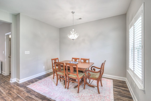 dining room with a wealth of natural light, baseboards, an inviting chandelier, and dark wood-style flooring