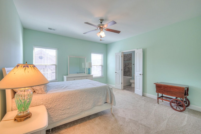 carpeted bedroom with visible vents, ensuite bath, baseboards, and a ceiling fan